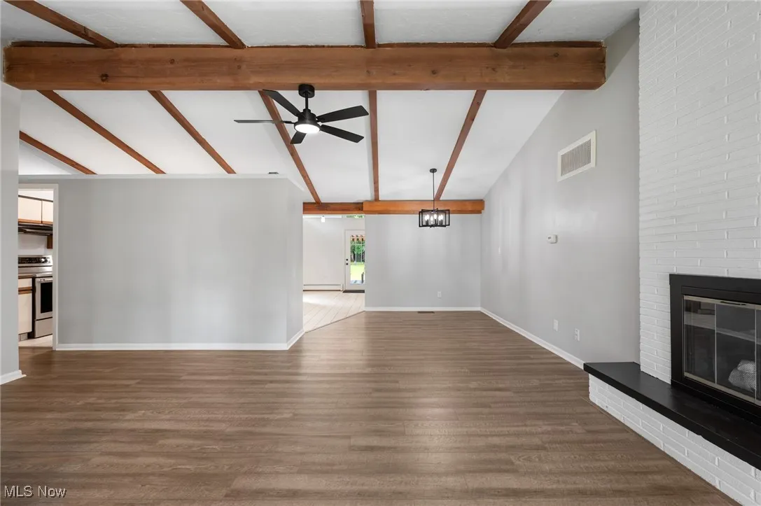 Unfurnished living room featuring a fireplace, a ceiling fan, and dark wood-style floors