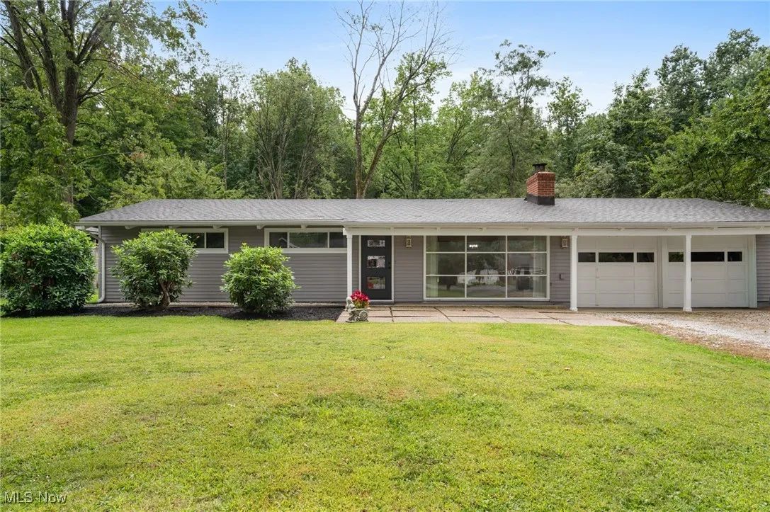 Single story home with a garage, a front yard, driveway, a chimney, and covered porch