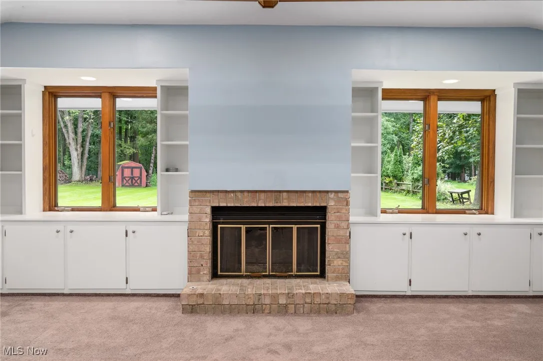 Unfurnished living room featuring light colored carpet and a fireplace