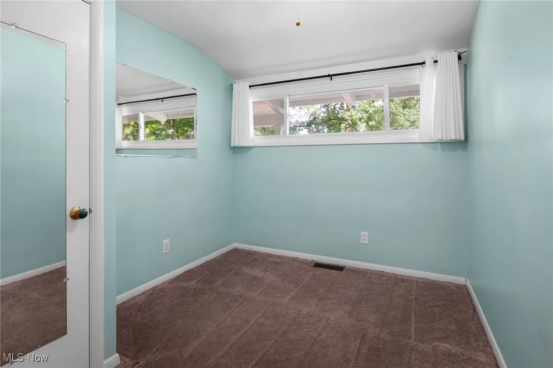 Unfurnished room with dark colored carpet and baseboards