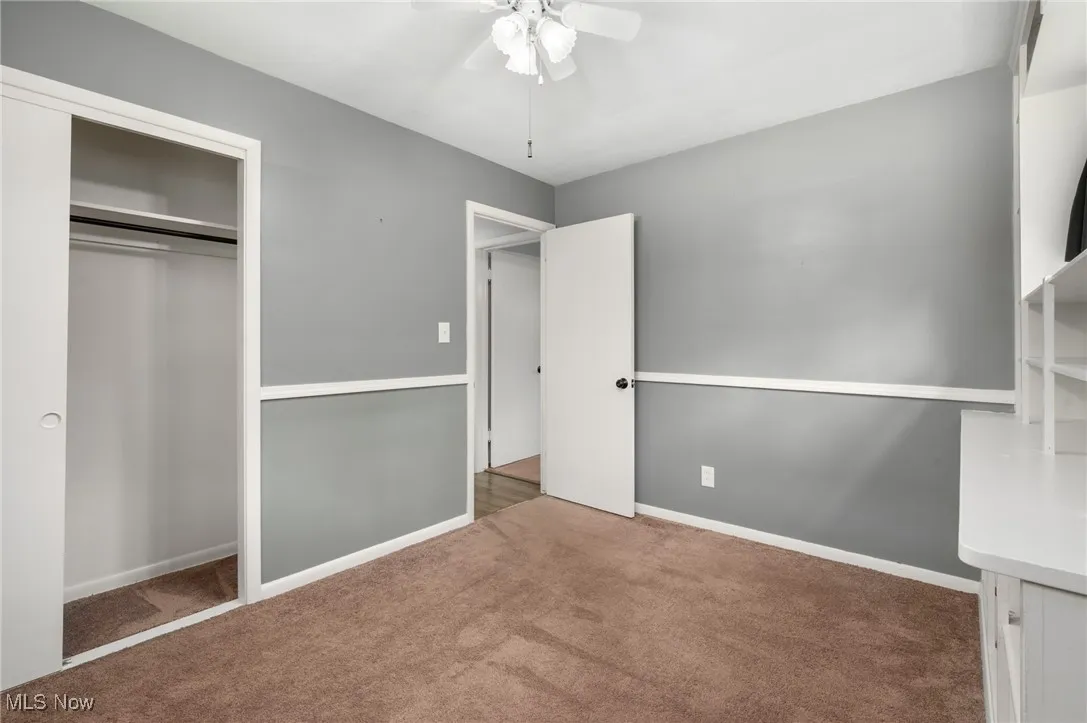 Unfurnished bedroom with carpet, a ceiling fan, and a closet