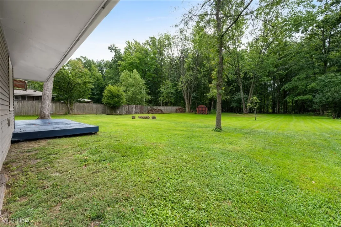 View of yard featuring a wooden deck, a storage unit, and view of wooded area