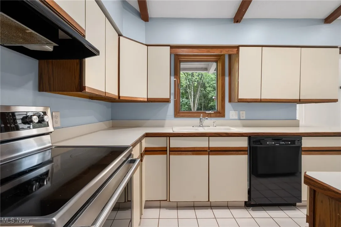 Kitchen featuring stainless steel electric stove, white cabinets, exhaust hood, light countertops, and beamed ceiling