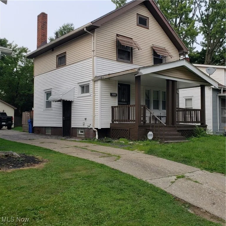 View of front facade featuring a chimney, a porch, and a front yard