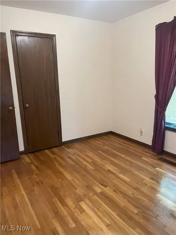 Unfurnished bedroom with hardwood / wood-style floors and baseboards