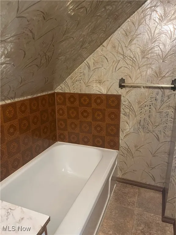 Bathroom featuring wallpapered walls and a garden tub