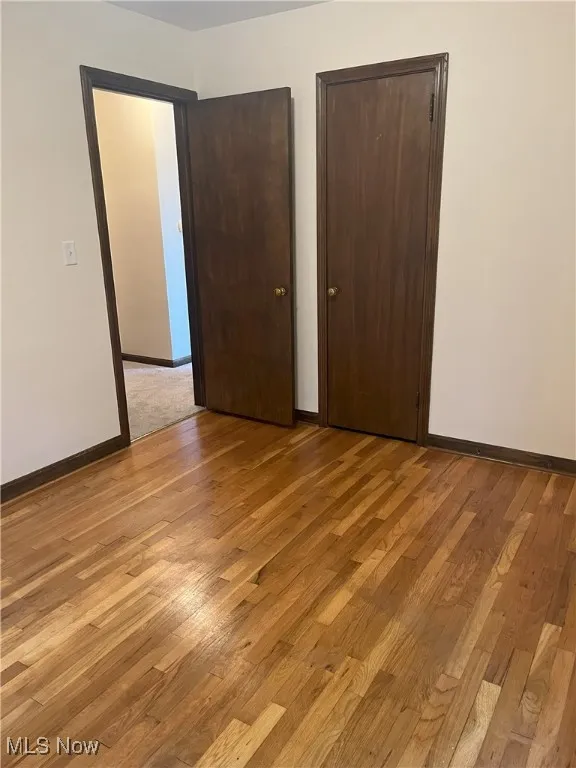 Unfurnished bedroom with light wood-type flooring and multiple closets