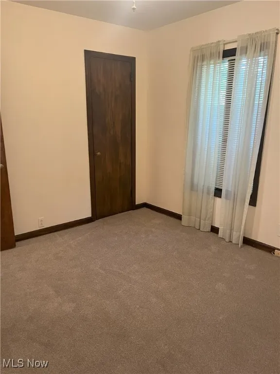 Unfurnished room with carpet flooring and baseboards