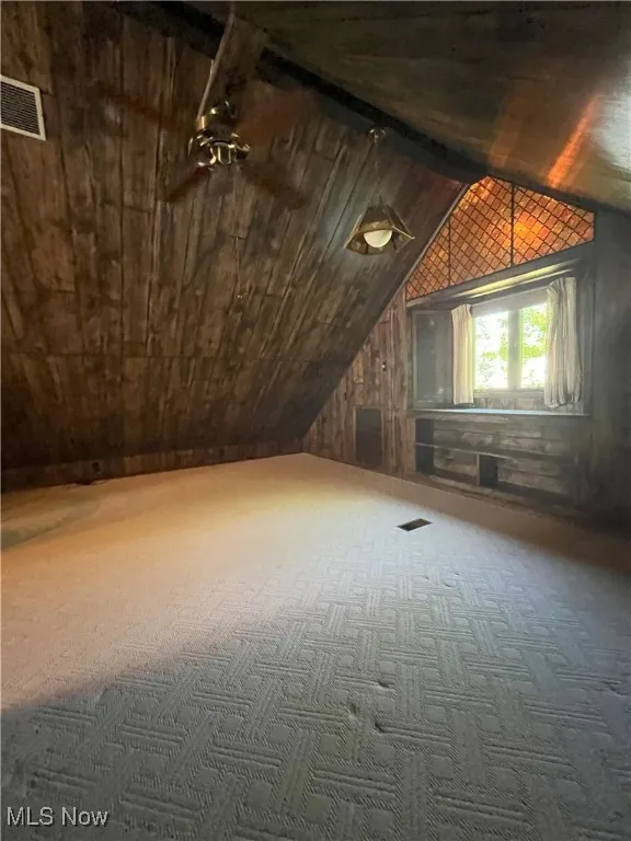 Bonus room with lofted ceiling, wooden ceiling, carpet, and wooden walls