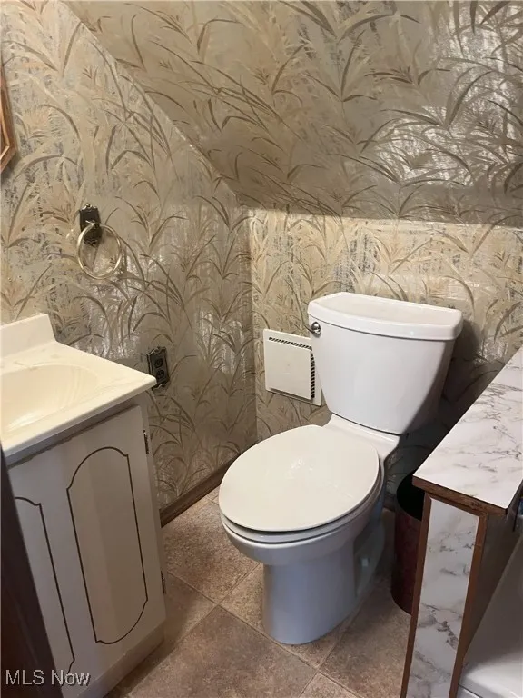 Half bath with vanity and wallpapered walls