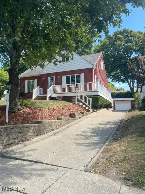 View of front of house featuring roof with shingles, an outdoor structure, and a detached garage