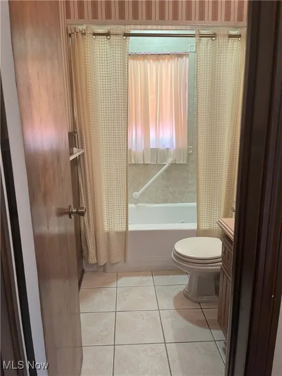 Bathroom with vanity, shower / bathtub combination with curtain, and light tile patterned floors