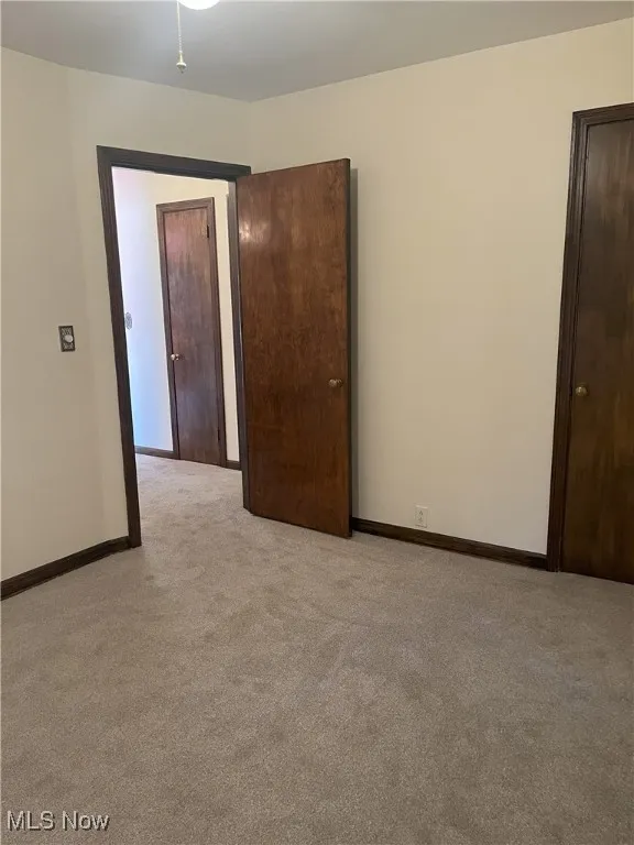 Spare room with light carpet and baseboards