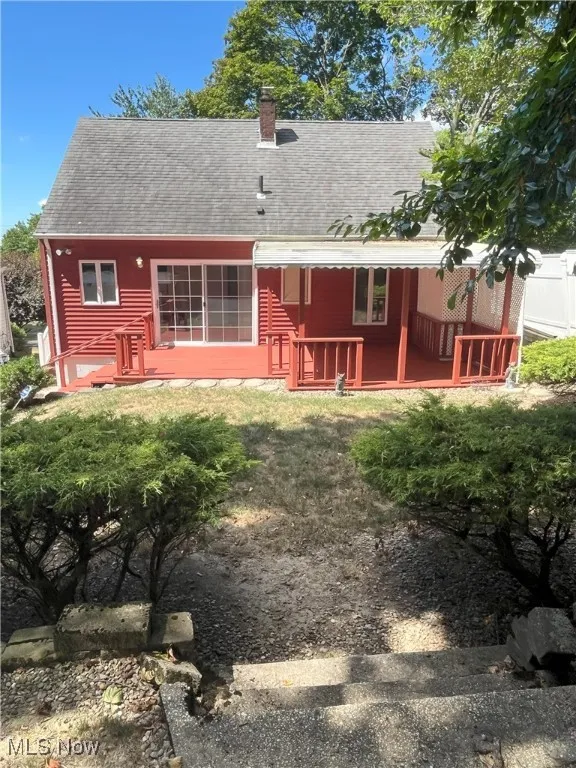 Rear view of property featuring roof with shingles and a chimney