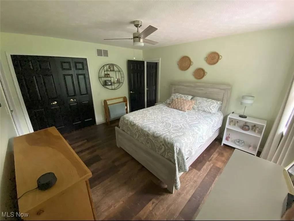 Bedroom featuring wood finished floors, a textured ceiling, a closet, and a ceiling fan