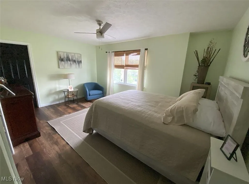 Bedroom with dark wood-type flooring, a textured ceiling, and ceiling fan