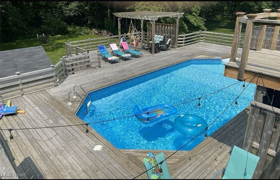 View of pool with a wooden deck and a lawn