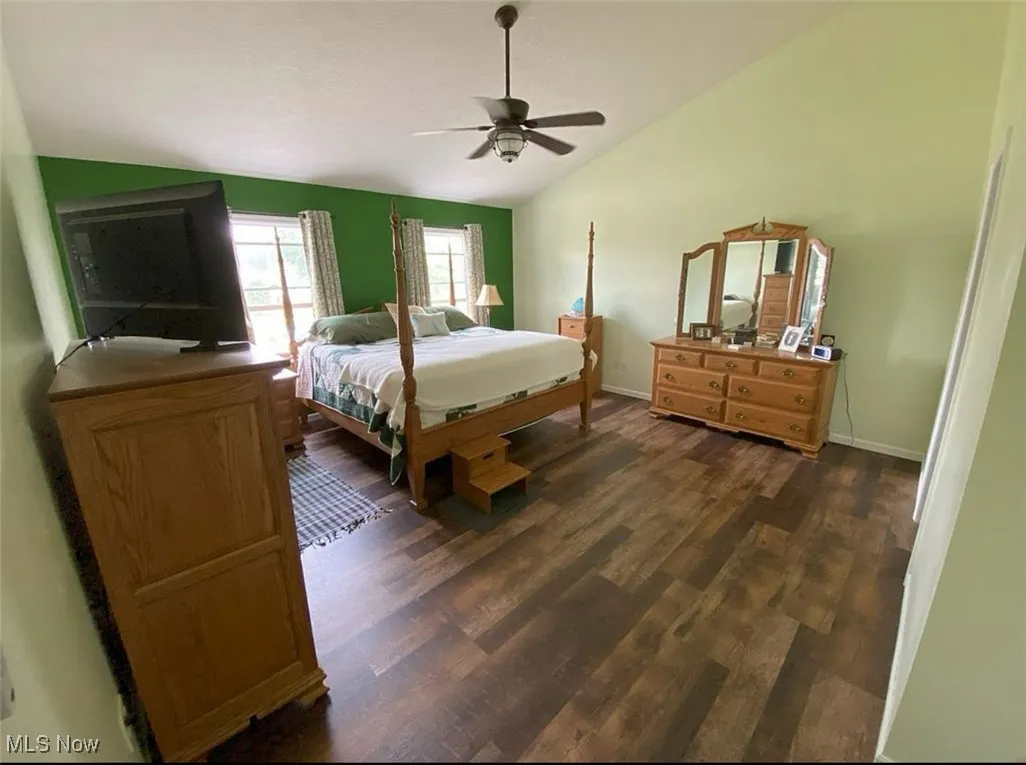 Bedroom with vaulted ceiling, dark wood-type flooring, and a ceiling fan