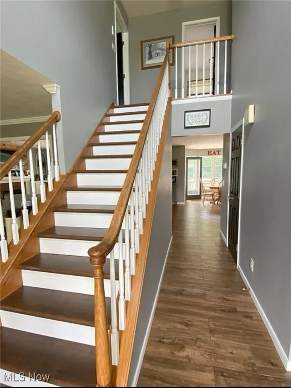 Stairway featuring wood finished floors and a towering ceiling