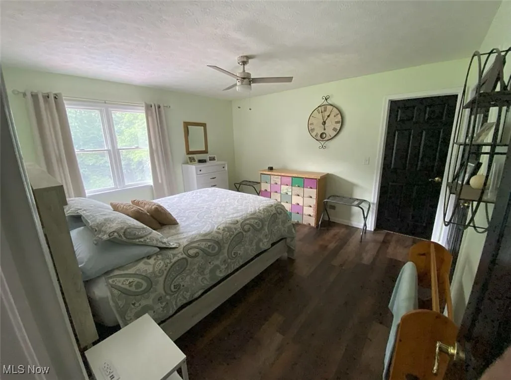 Bedroom with dark wood-style flooring, a textured ceiling, and ceiling fan