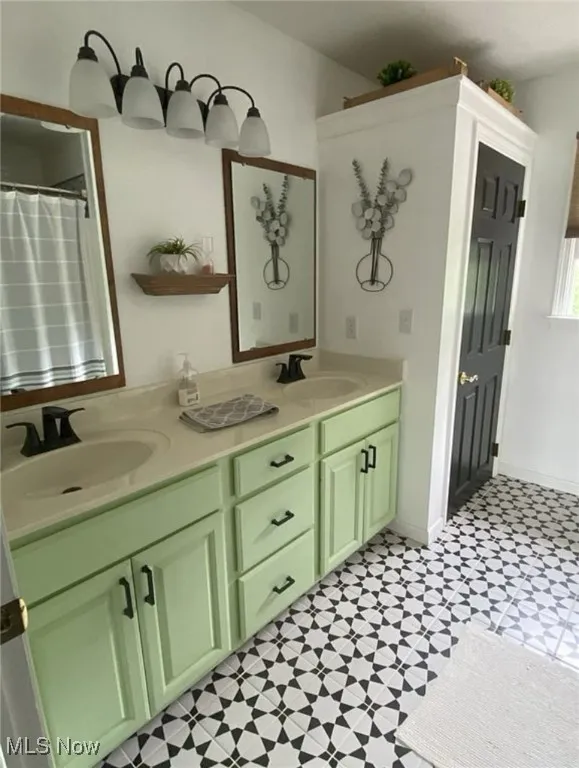 Bathroom featuring double vanity, light flooring, and a shower with shower curtain