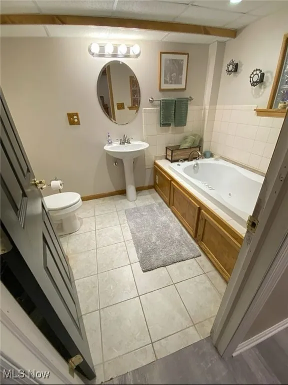 Full bath featuring a whirlpool tub, light tile patterned flooring, and a paneled ceiling