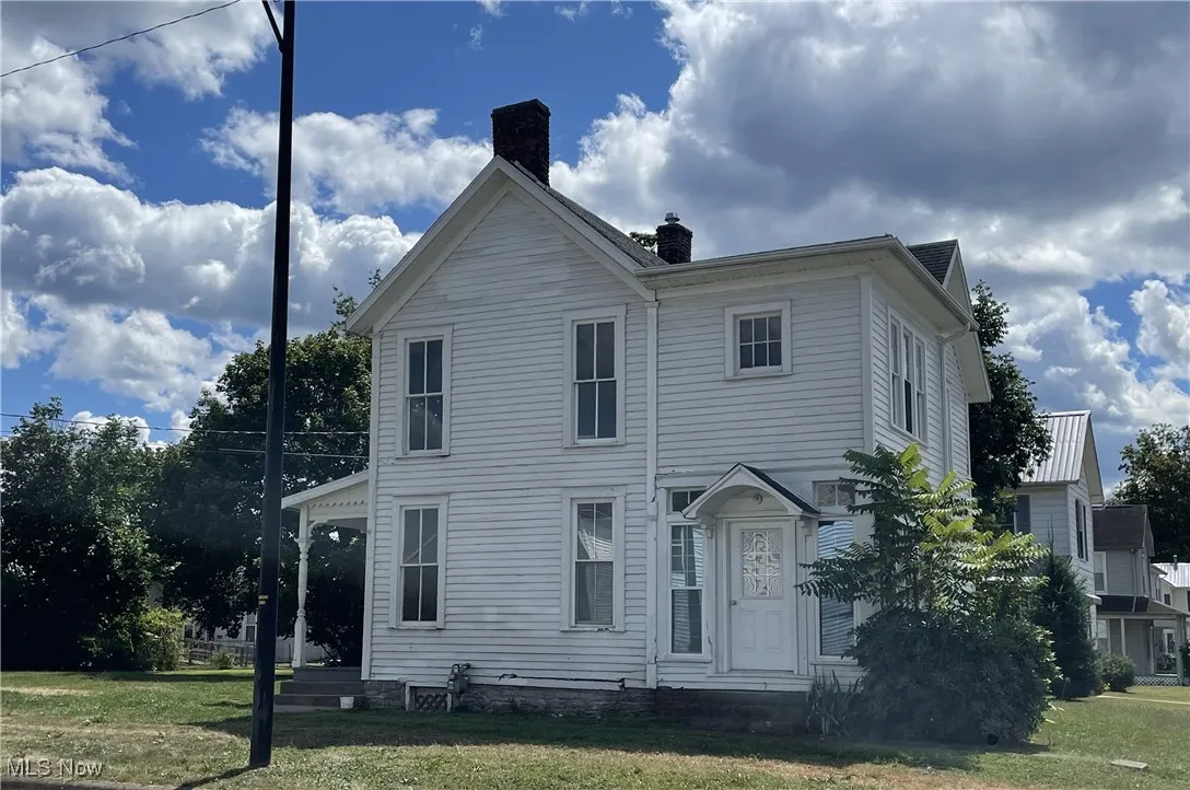 View of left side of home featuring a chimney and a side yard