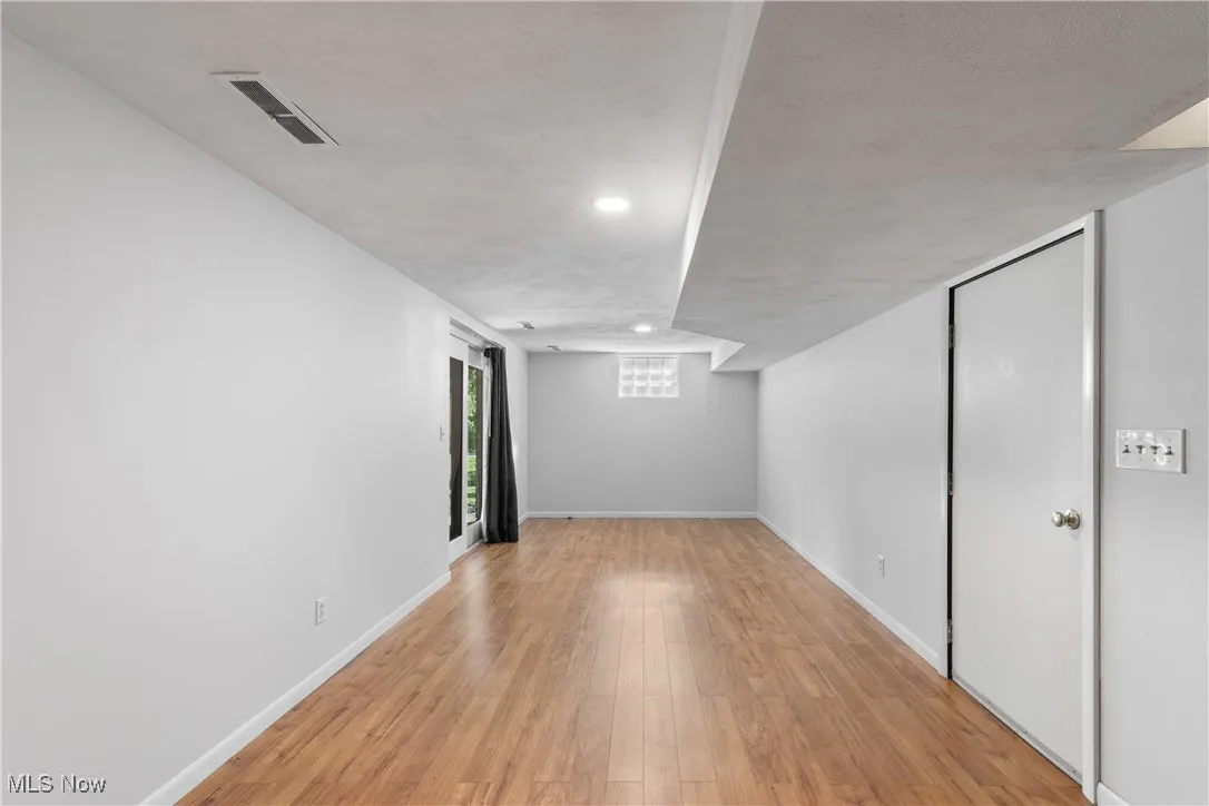finished walkout lower level grade area featuring light wood-type flooring and baseboards