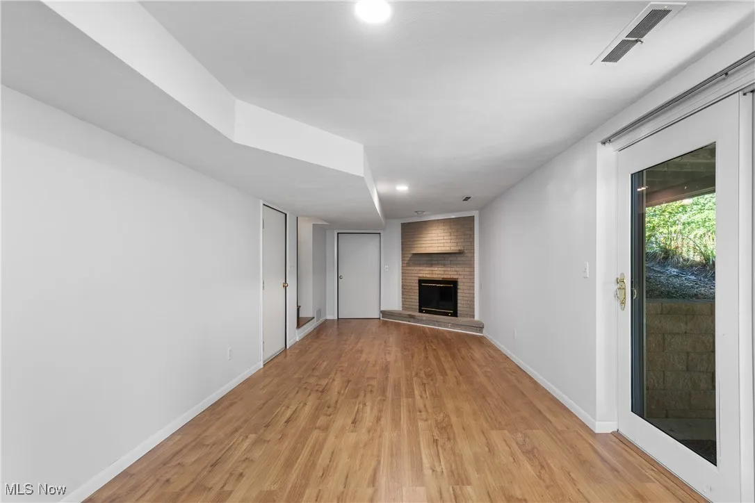 Finished walk-out lower level living room featuring a fireplace, light wood-style floors, and recessed lighting