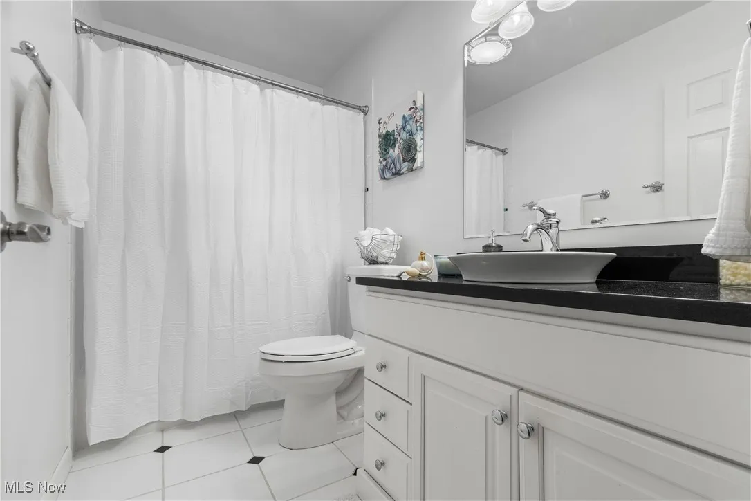 Bathroom with light tile patterned floors, vanity, and a shower with curtain