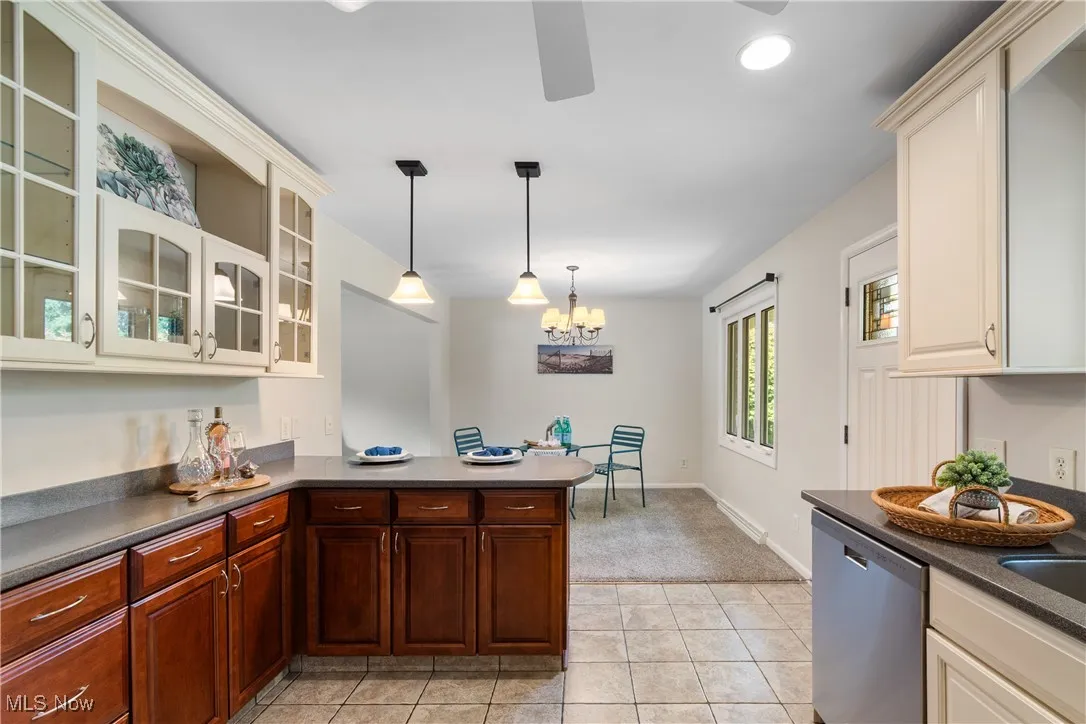 Kitchen with dark countertops, dishwasher, a peninsula, glass insert cabinets, and recessed lighting