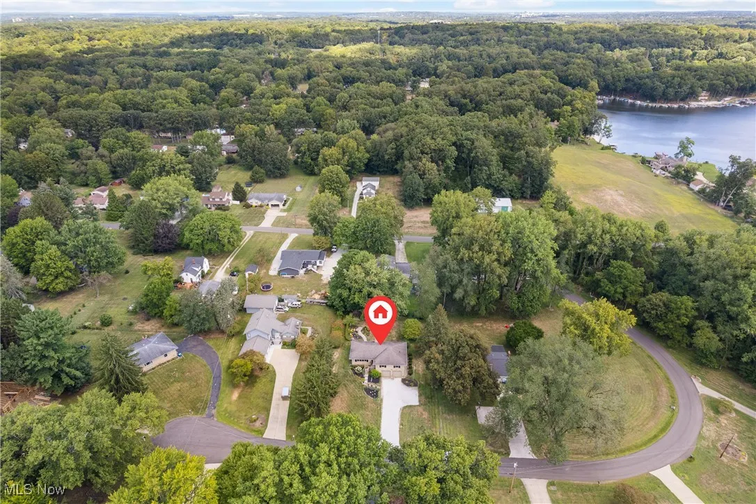 Aerial perspective of suburban area with a nearby body of water and a heavily wooded area