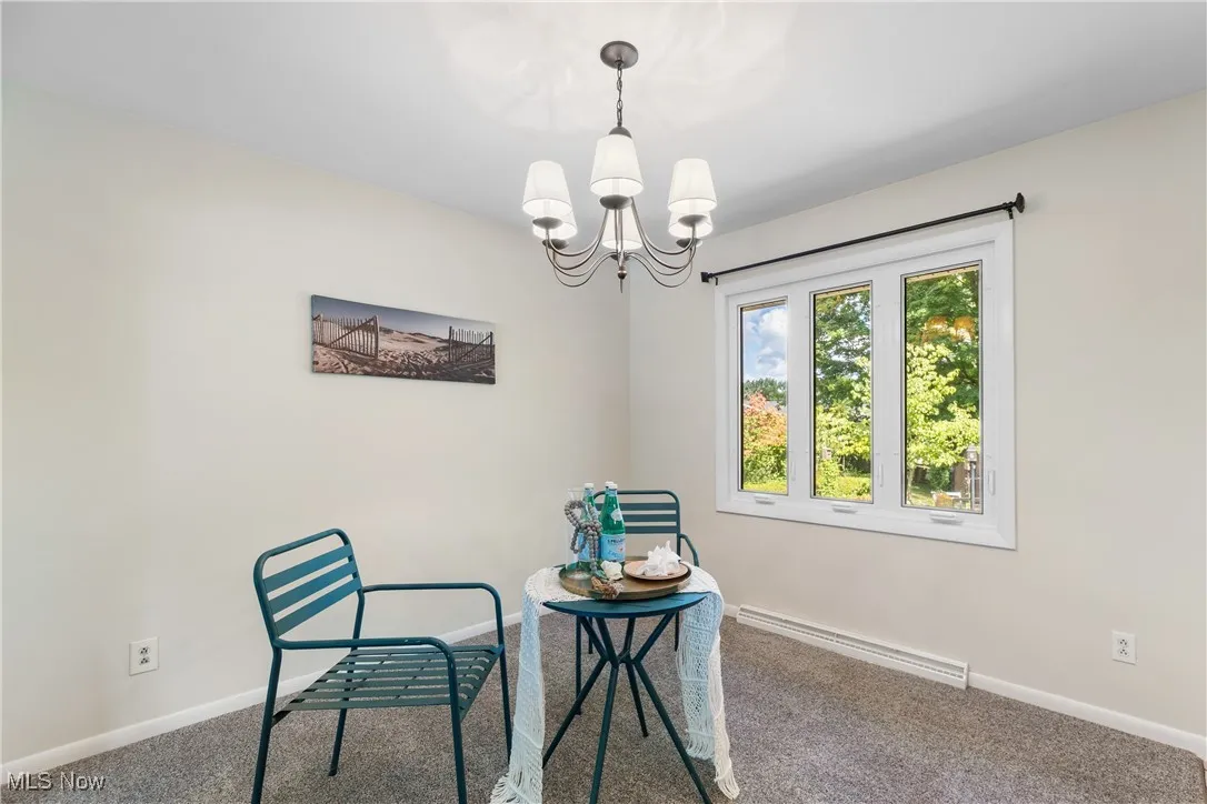 Carpeted dining space featuring a baseboard heating unit and a chandelier