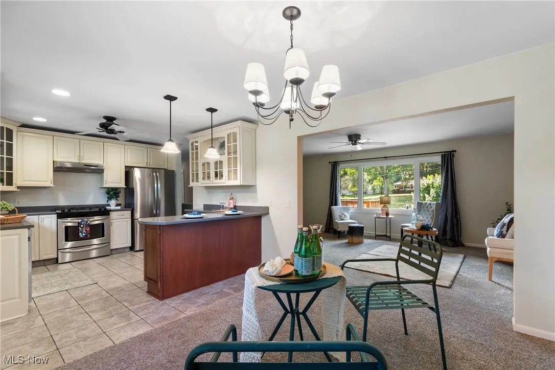 Kitchen with a ceiling fan, glass insert cabinets, appliances with stainless steel finishes, cream cabinets, and recessed lighting