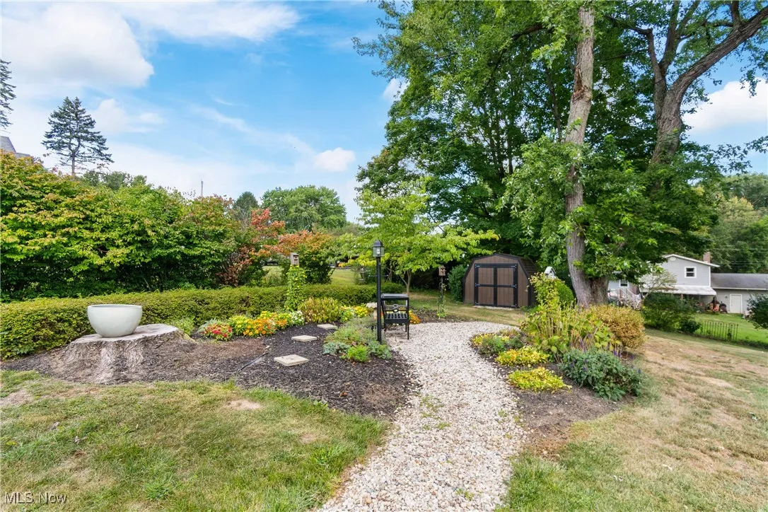 View of grassy yard featuring a storage shed and view of wooded area