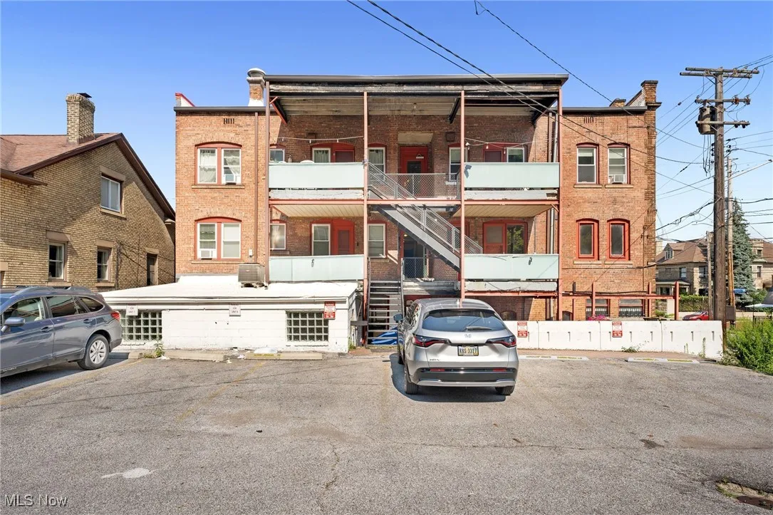 View of building exterior featuring stairway and uncovered parking