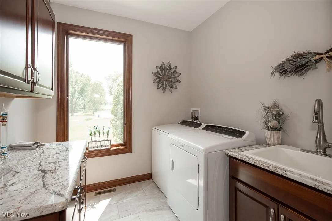 Laundry room featuring healthy amount of natural light, cabinet space, independent washer and dryer, and light tile patterned floors