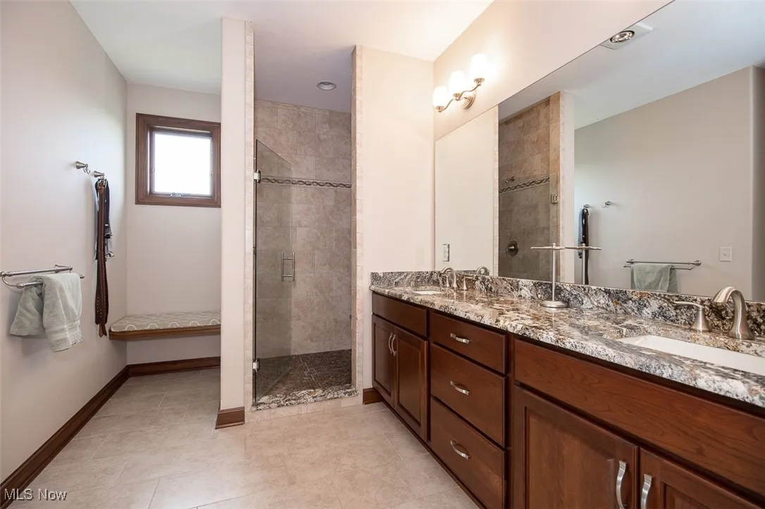 Full bathroom featuring double vanity, a shower stall, and light tile patterned floors
