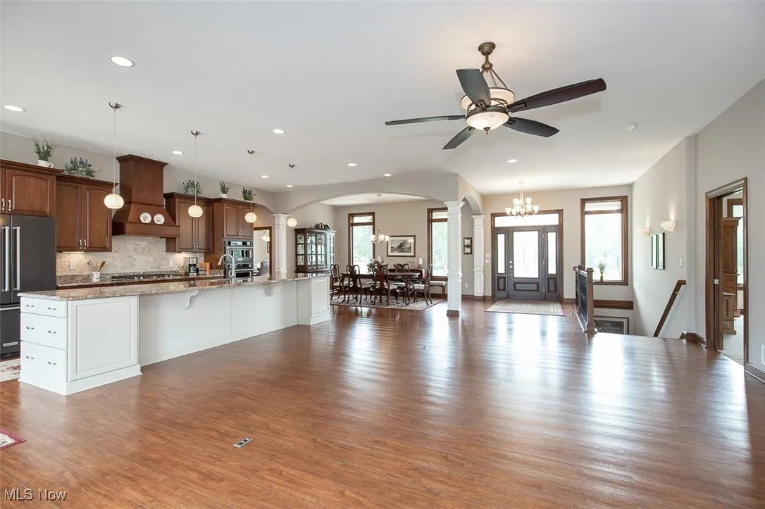 Kitchen with open floor plan, decorative columns, a kitchen breakfast bar, arched walkways, and decorative backsplash