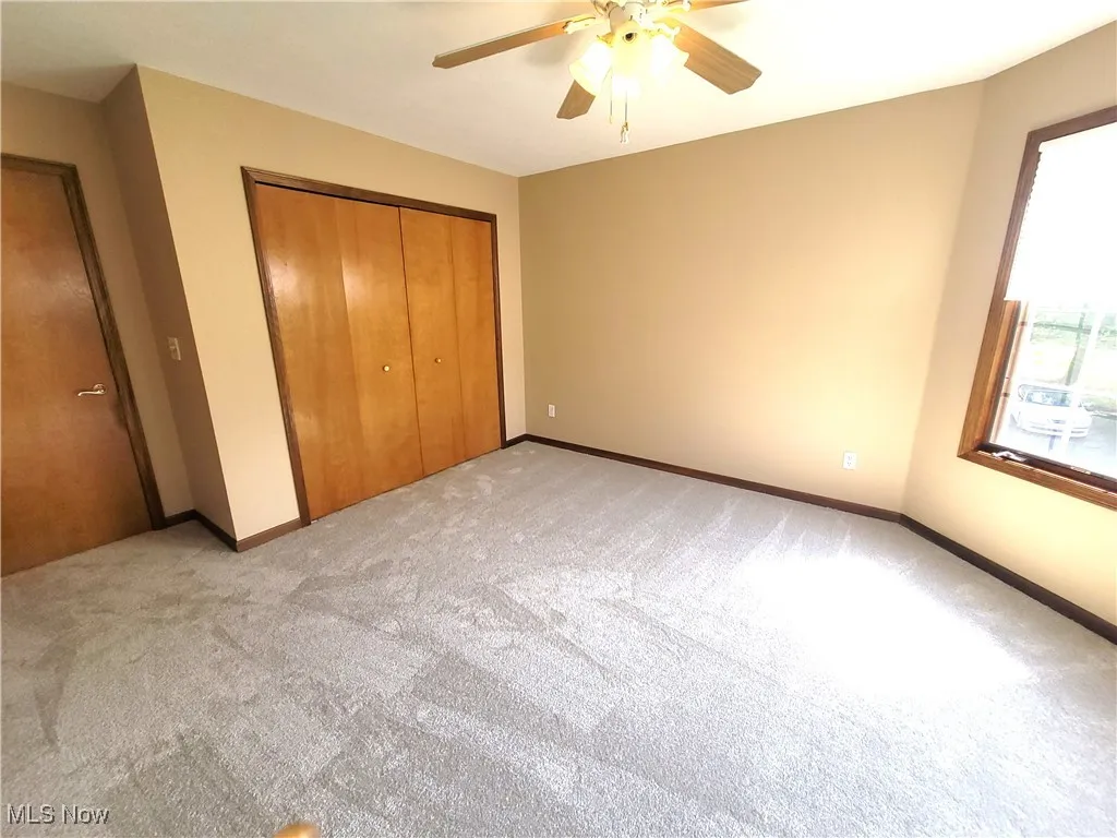 Unfurnished bedroom featuring light colored carpet, a closet, and ceiling fan
