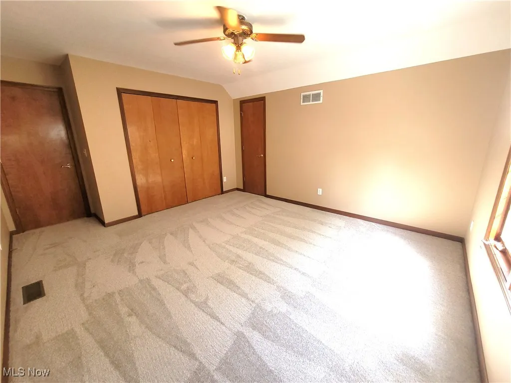 Unfurnished bedroom featuring light carpet, a ceiling fan, and a closet