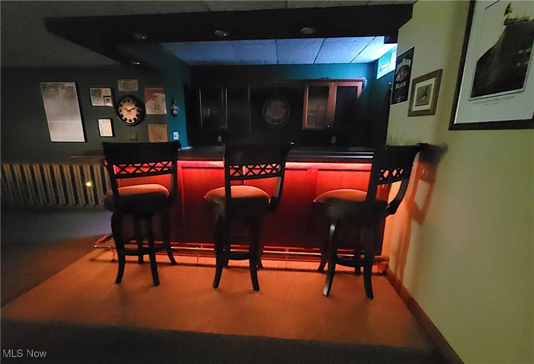 Indoor dry bar featuring dark countertops and a drop ceiling