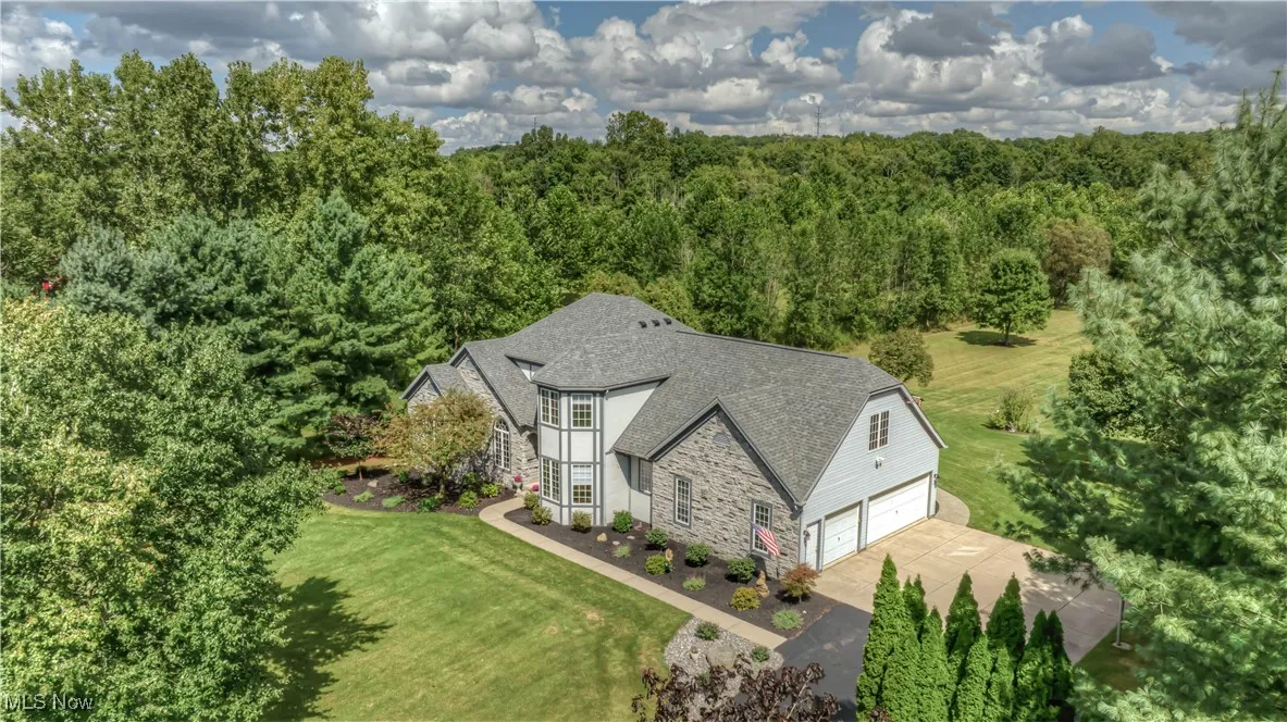 Aerial view of property and surrounding area with a heavily wooded area