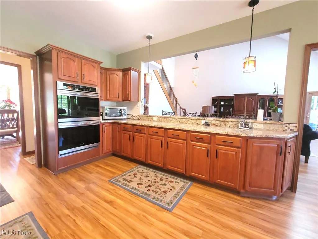 Kitchen with stainless steel appliances, brown cabinets, pendant lighting, and a peninsula