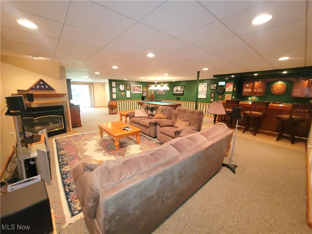 Living area with carpet, a drop ceiling, a glass covered fireplace, bar, and recessed lighting