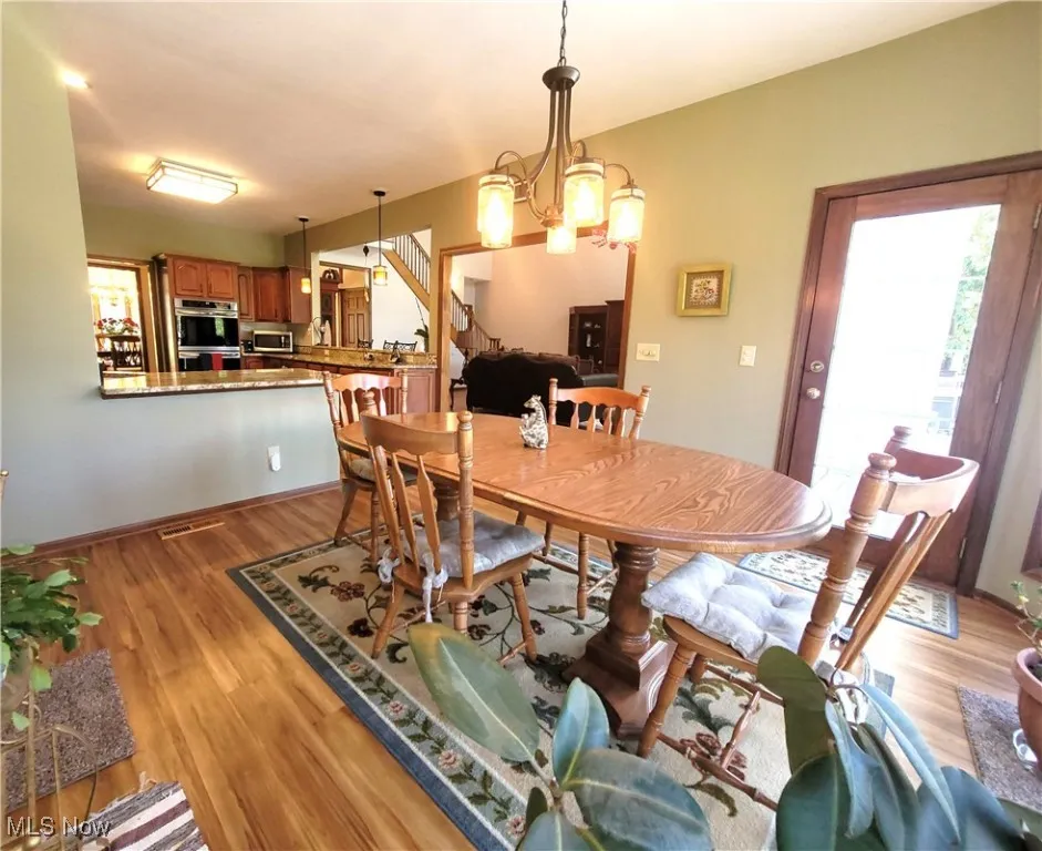 Dining area with light wood-style floors, a chandelier, and stairs