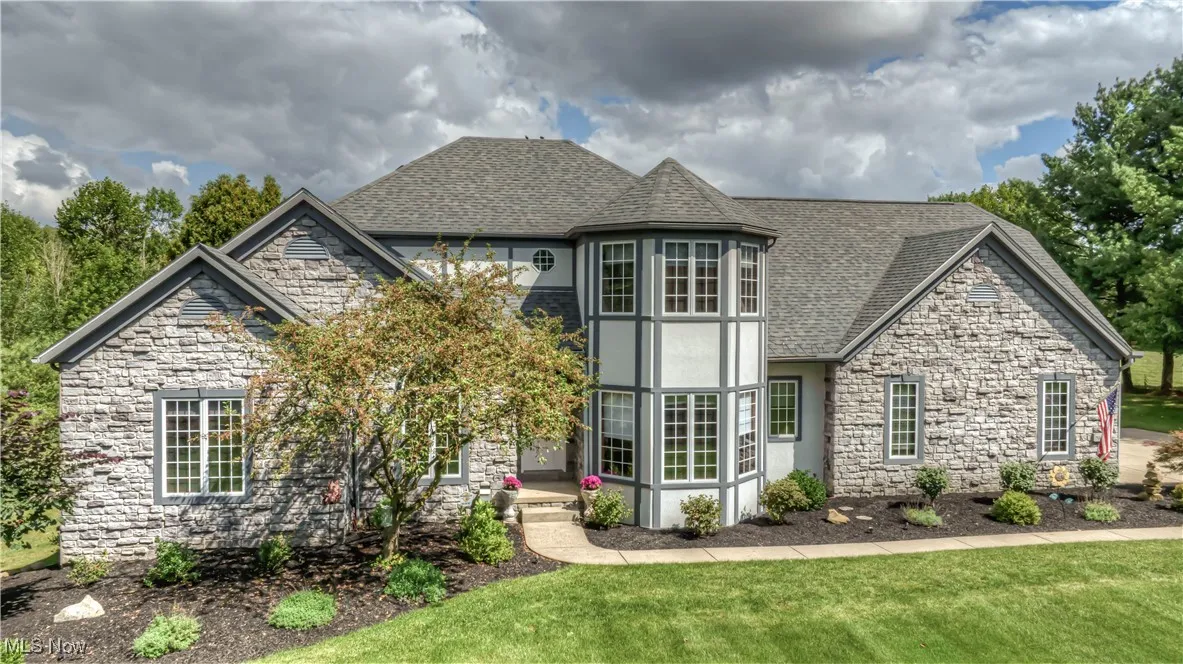 View of front of property with roof with shingles, stone siding, stucco siding, and a front lawn