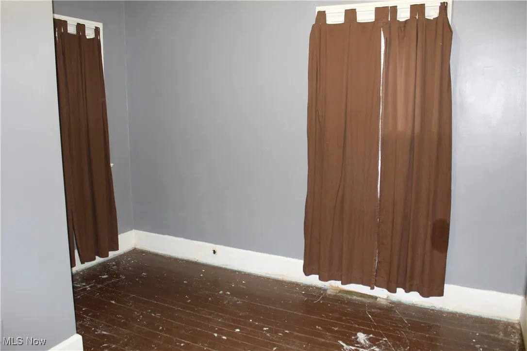 Unfurnished bedroom featuring baseboards and dark wood-style floors