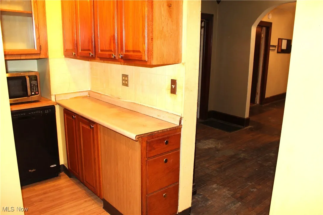 Kitchen light countertops, light wood-type flooring, backsplash, and appliances
