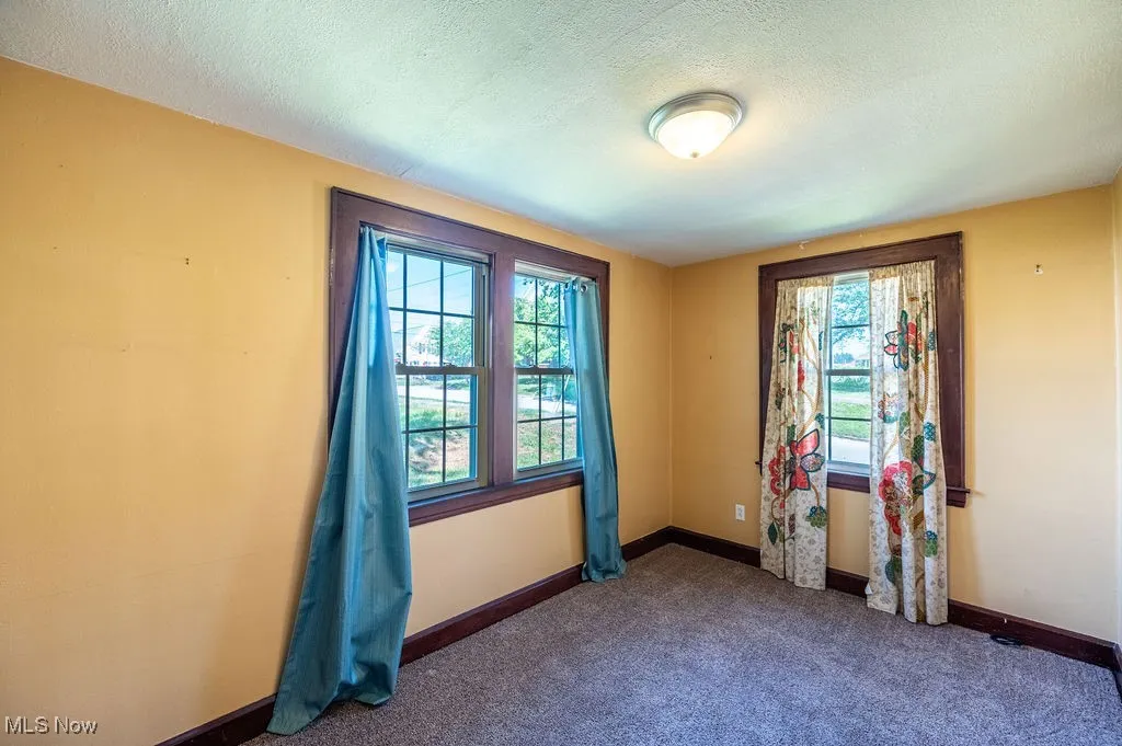 Unfurnished room featuring dark carpet and a textured ceiling
